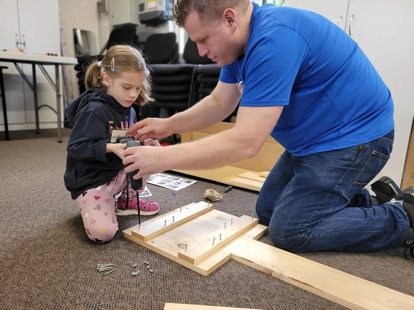 An adult and a child working together to build a billy cart from timber